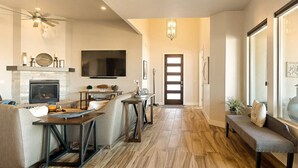 A spacious living area with a fireplace, a television, and a dining area with a bench.
