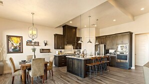 A spacious kitchen with dark wood cabinets, a central island with bar stools, and modern appliances.