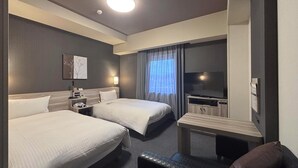 A hotel room with two beds, a desk, a flat-screen TV, and a window with curtains.