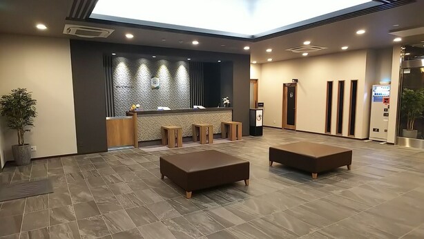 A lobby with a reception desk, seating area, and a vending machine.