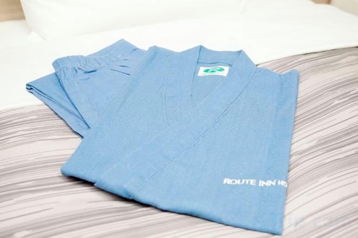 Una camiseta azul con el texto 'ROUTE INN' doblada sobre una cama.