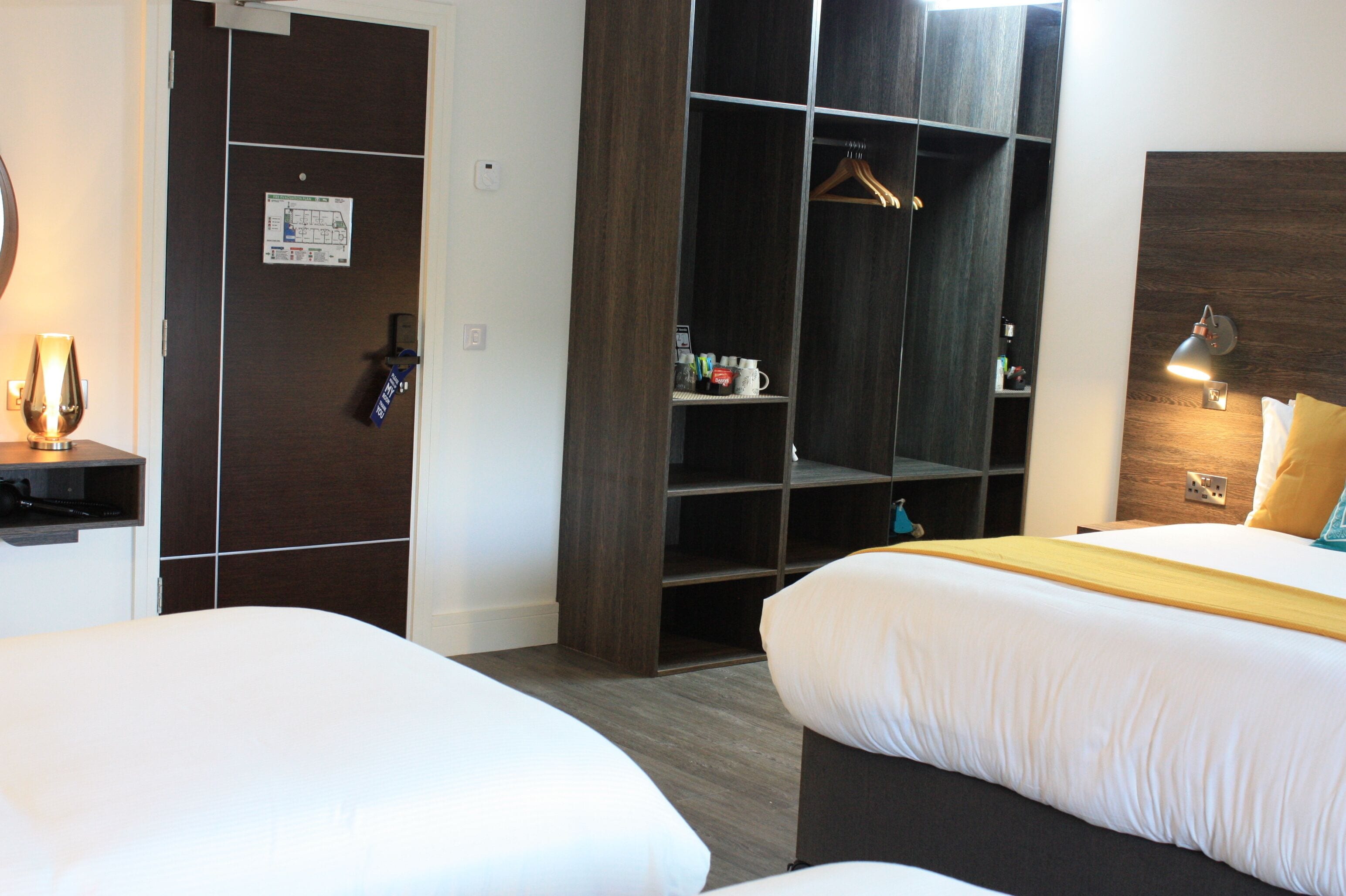Ett hotellrum med två sängar, en garderob, ett skrivbord och en sänglampa.