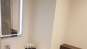 A modern bathroom with a white sink, mirror, and toilet. There are towels and toiletries on the sink. - Base Accommodation Dingle (Dingle)