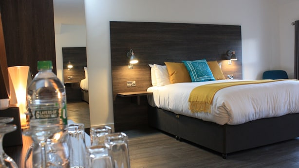 A hotel room with a large bed, bedside tables, and a nightstand. - Base Accommodation Dingle (Dingle)