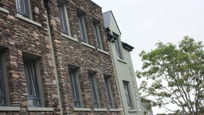 A stone building with multiple windows and a tree in the foreground. - Base Accommodation Dingle (Dingle)