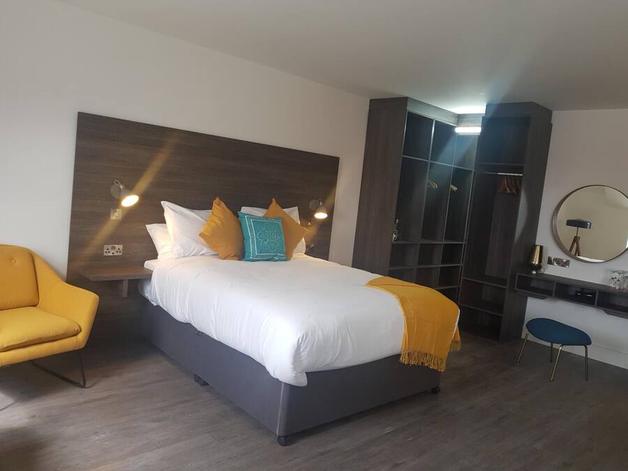Une chambre moderne avec un grand lit, une table de chevet, une armoire, un bureau et une chaise.