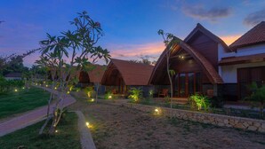 A row of bungalow-style cottages with pitched roofs, surrounded by a landscaped garden with pathways and small trees. - Tahoma Villas Labuan Bajo by ABM (Labuan Bajo)