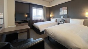 Una camera d'albergo con due letti, una scrivania, una TV e una finestra con tende.