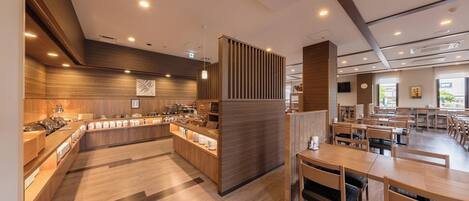 Un café moderno con muebles de madera, una barra con productos alimenticios y un área de estar con mesas y sillas.