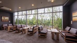 Un'area lounge moderna con ampie finestre, diverse disposizioni di sedute e un pavimento rivestito di moquette.