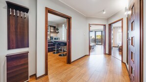 A hallway with wooden flooring, a mirror, and a door leading to a balcony with outdoor seating. - Apartamenty Sun & Snow Jasny Brzeg (Wladyslawowo)