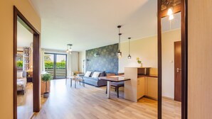 A modern living room with a sofa, a dining table, and a kitchen area. - Apartamenty Sun & Snow Jasny Brzeg (Wladyslawowo)