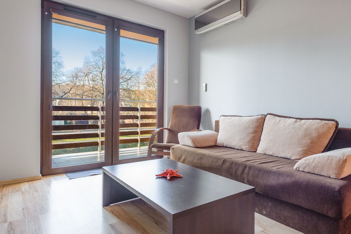 Ein modernes Wohnzimmer mit einer Couch, einem Couchtisch und einer Glasschiebetür, die auf einen Balkon führt.