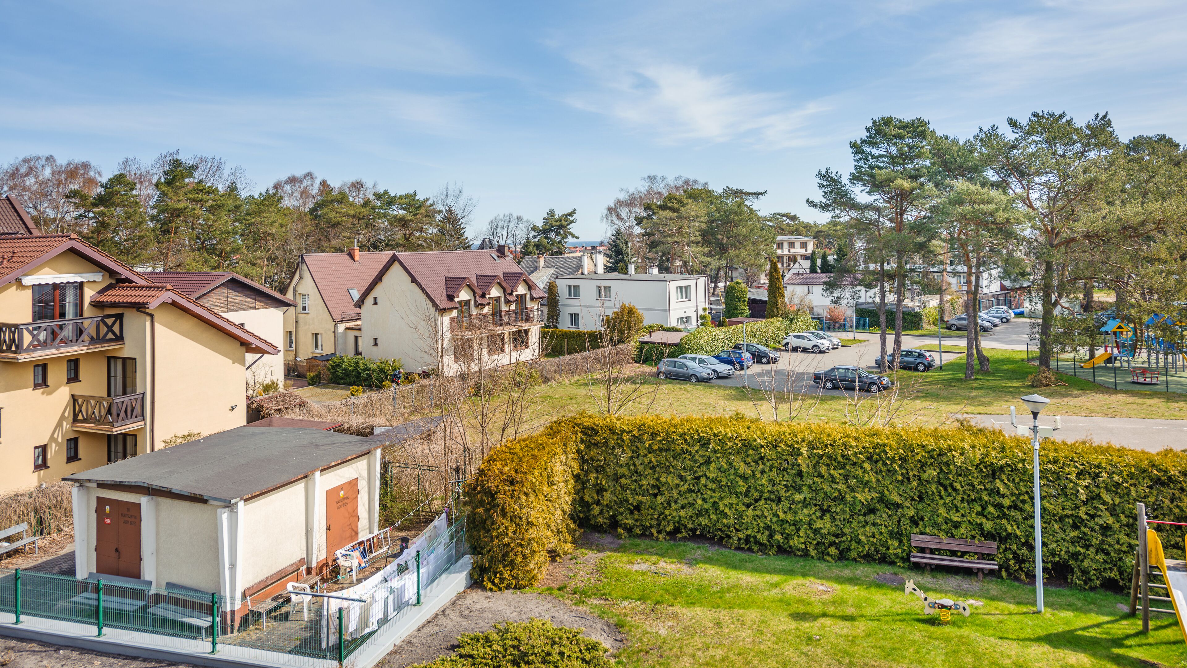Un quartiere residenziale con case, un parco giochi e auto parcheggiate.
