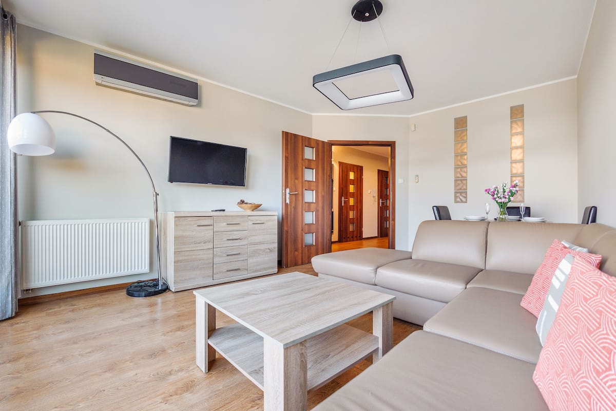 Ein modernes Wohnzimmer mit einer Couch, einem Couchtisch, einem Fernseher und einem Essbereich mit Tisch und Stühlen.