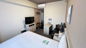 A hotel room with a bed, a TV, a desk, and a chair.