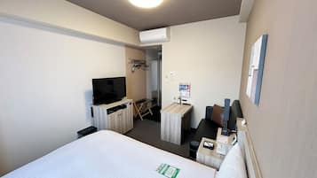 Een hotelkamer met een bed, een televisie, een bureau en een stoel.