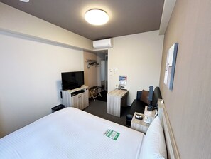 A hotel room with a bed, a TV, a desk, and a chair.