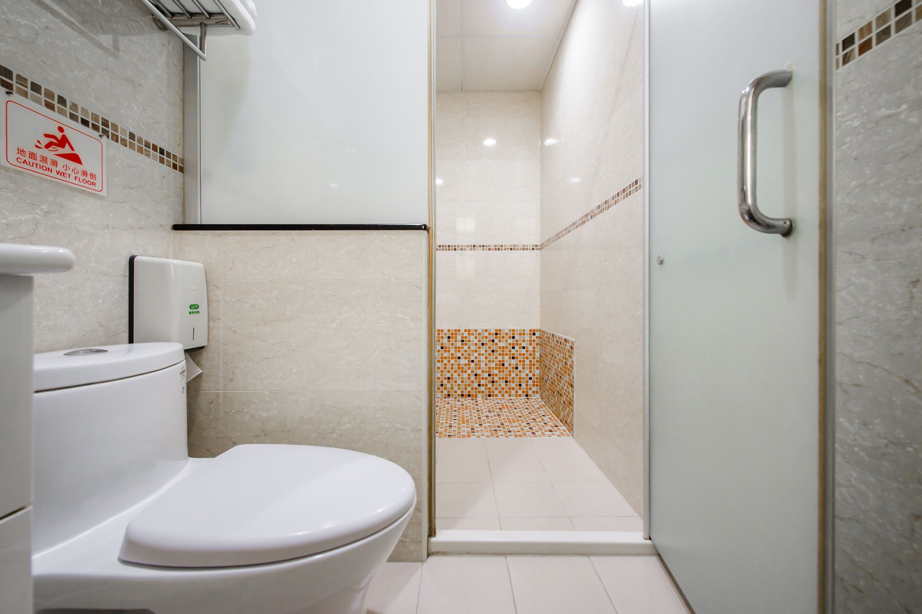 A modern bathroom with a toilet, a hand dryer, and a glass-enclosed shower area.