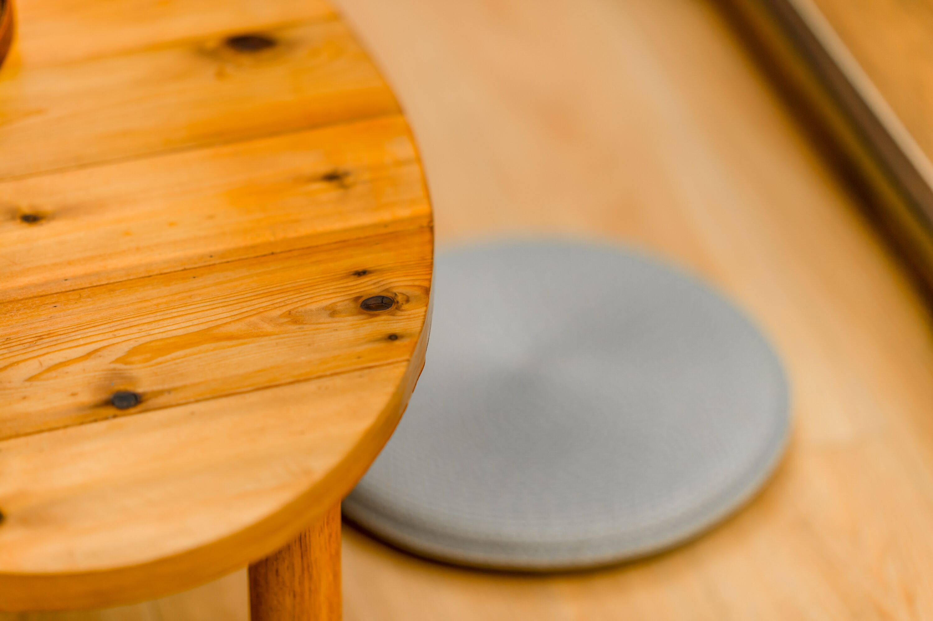 Una mesa de madera con un plato gris sobre un piso de madera.