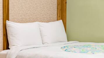 A bed with white linens and a colorful blanket, a wooden headboard, and a patterned wall.