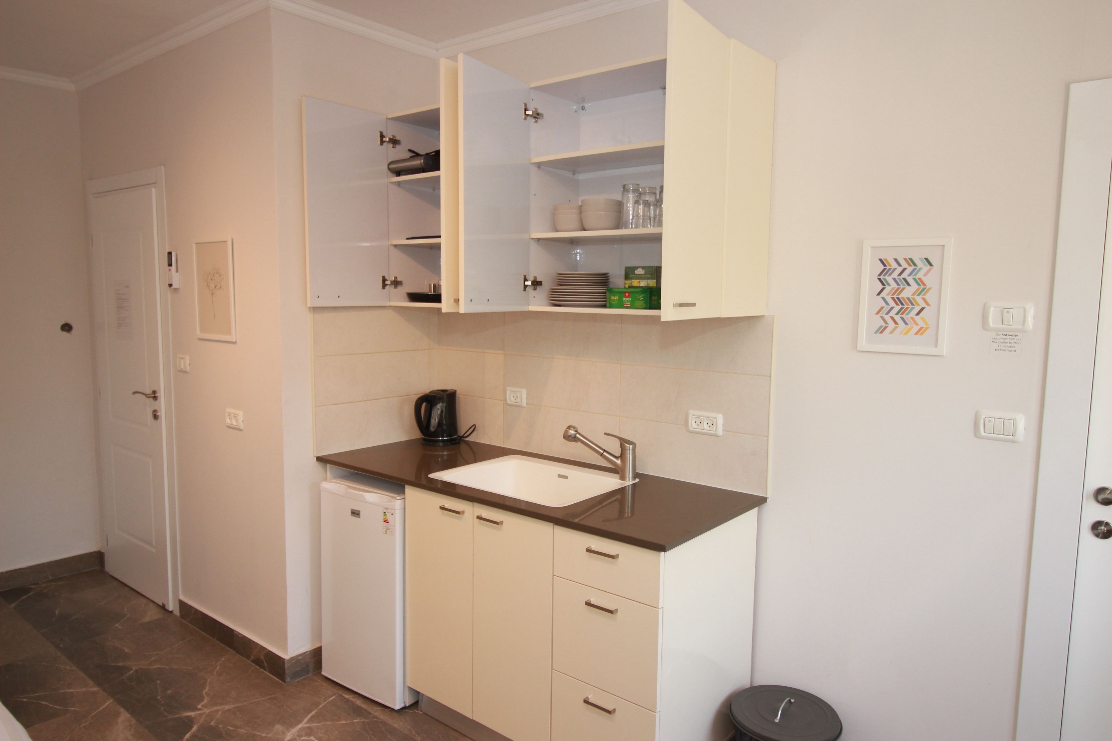 A compact kitchen with a built-in dishwasher, a sink, and a coffee maker.