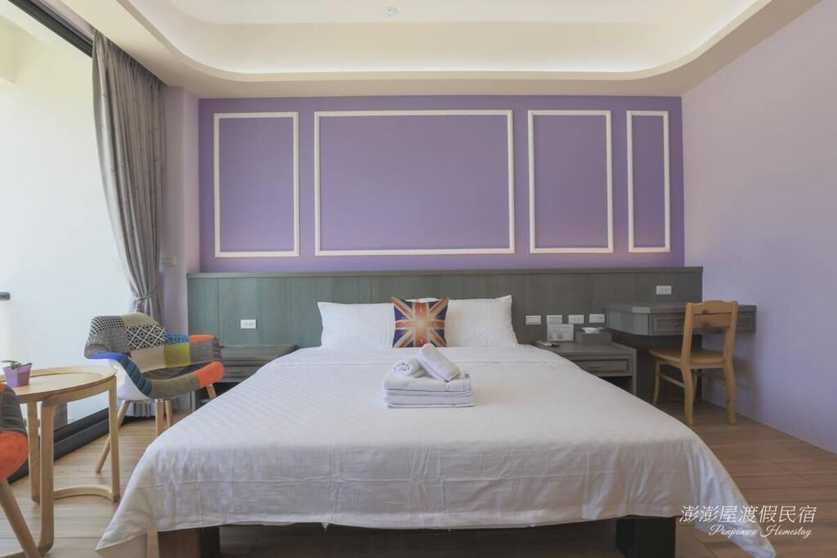 A hotel room with a large bed, a desk, and a chair.