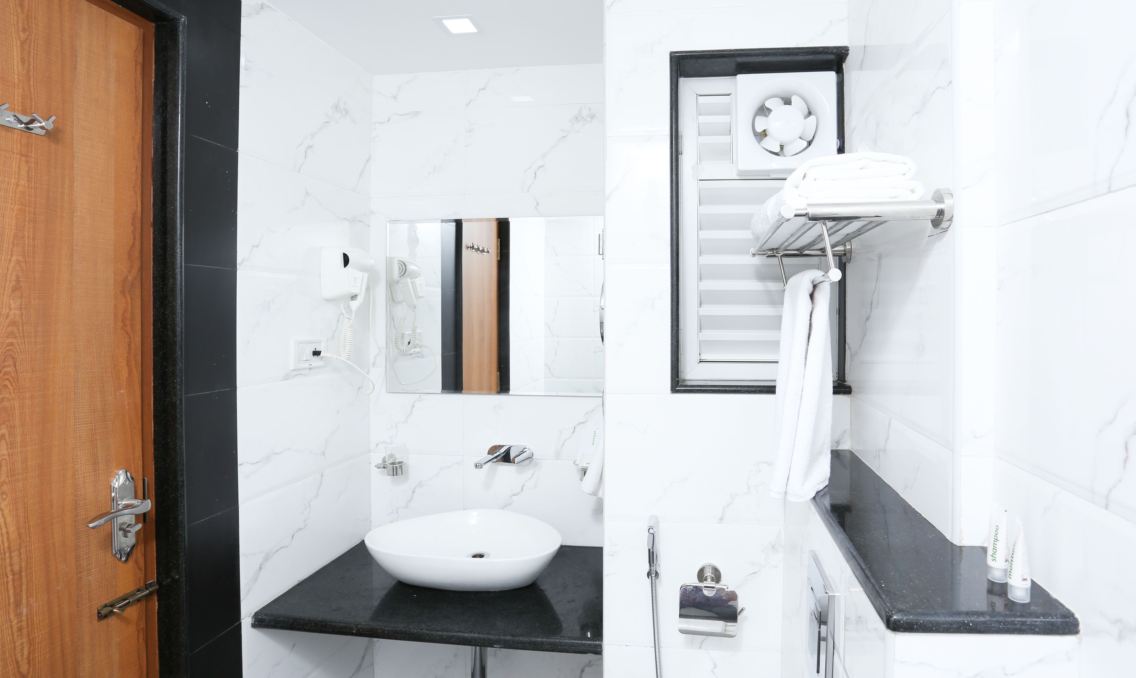A modern bathroom with a white sink, a mirror, a towel rack, and a shower.