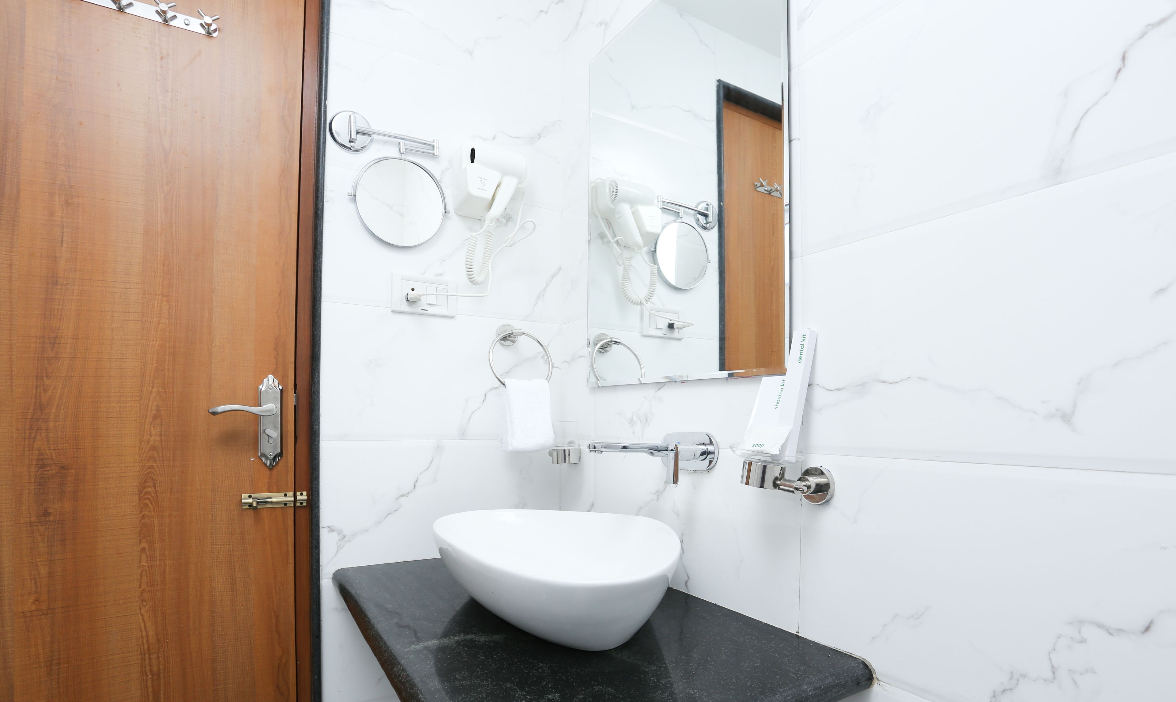 Un baño con un lavabo blanco, un espejo y un secador de pelo en la pared.