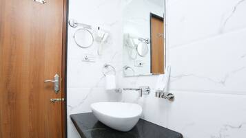 Un baño con un lavabo blanco, un espejo y un secador de pelo en la pared.