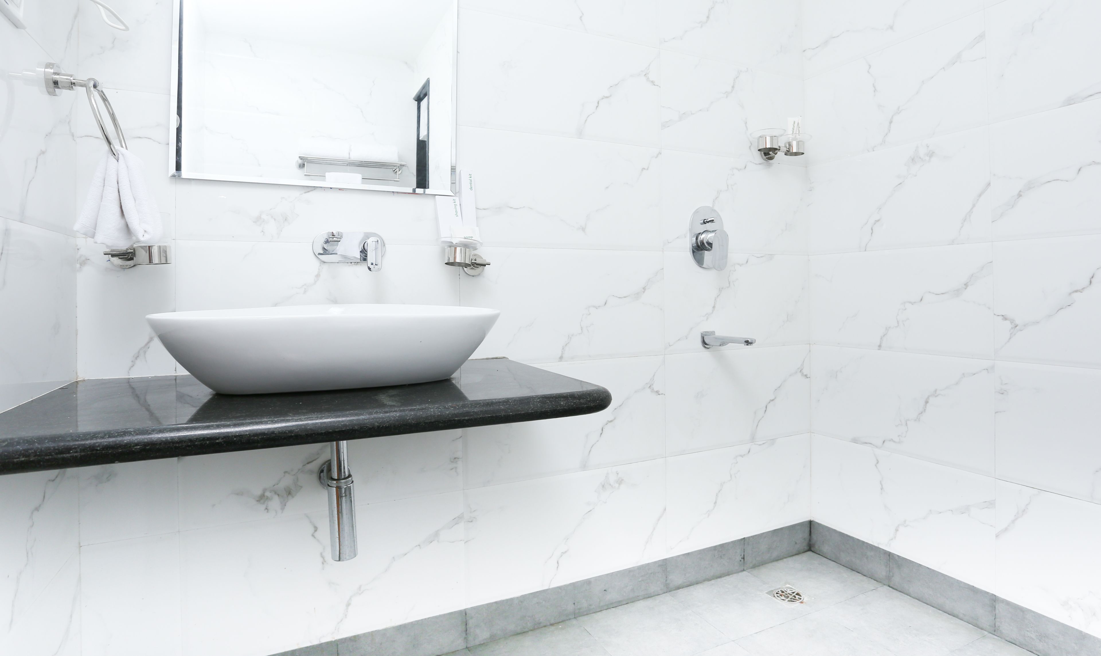 A bathroom with a white marble sink, chrome fixtures, and a mirror above the sink.