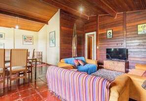 Um quarto acolhedor com sofá, cadeiras, televisão e paredes de madeira.