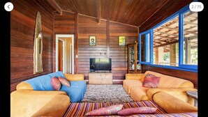 Una habitación acogedora de estilo cabaña, con paredes de madera, un televisor y dos sofás con cojines de colores.