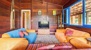 Um interior em madeira com dois sofás, uma televisão e um tapete.