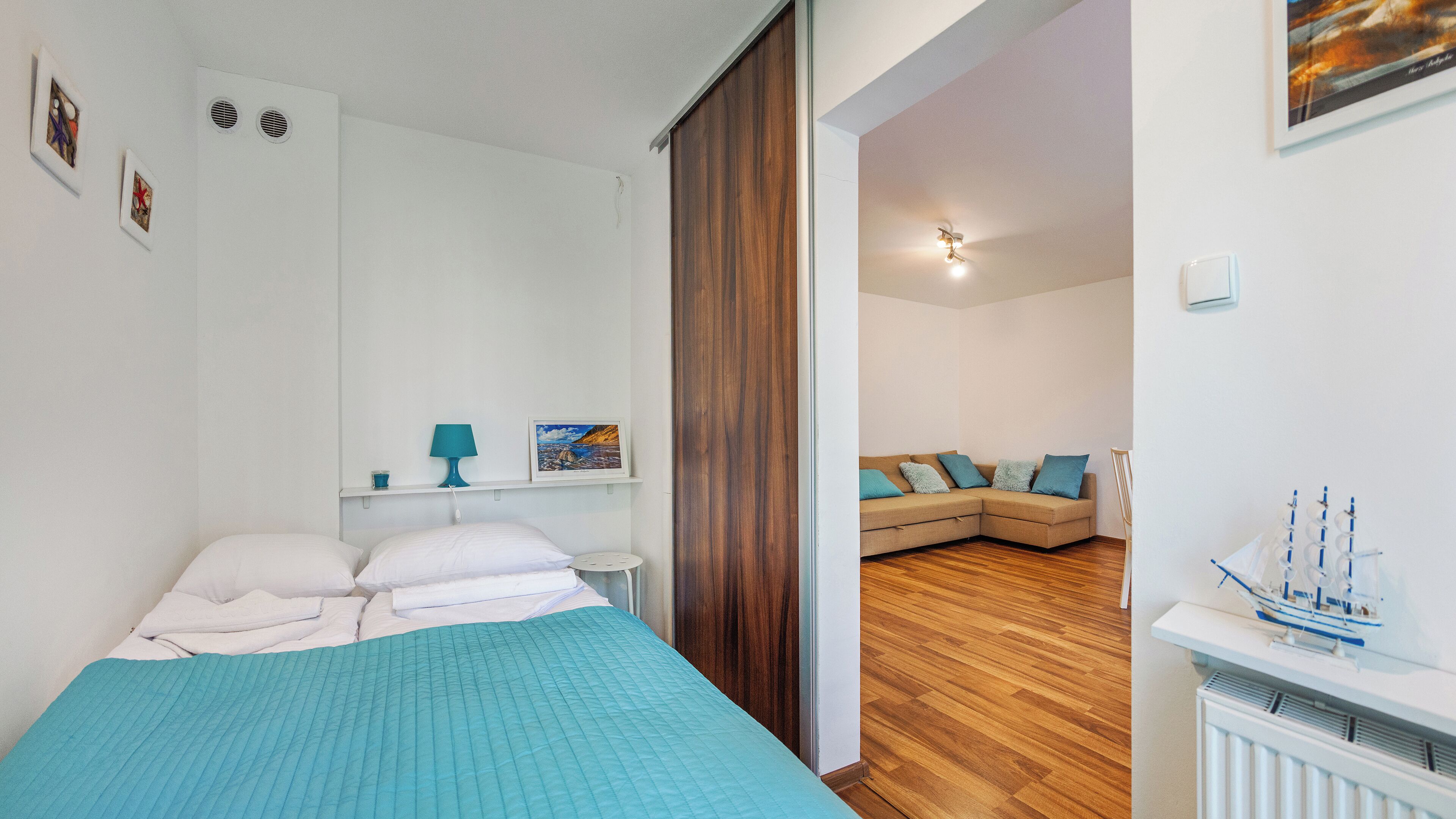Une chambre à coucher avec un lit, une table de chevet, une lampe et un cadre photo accroché au mur.
