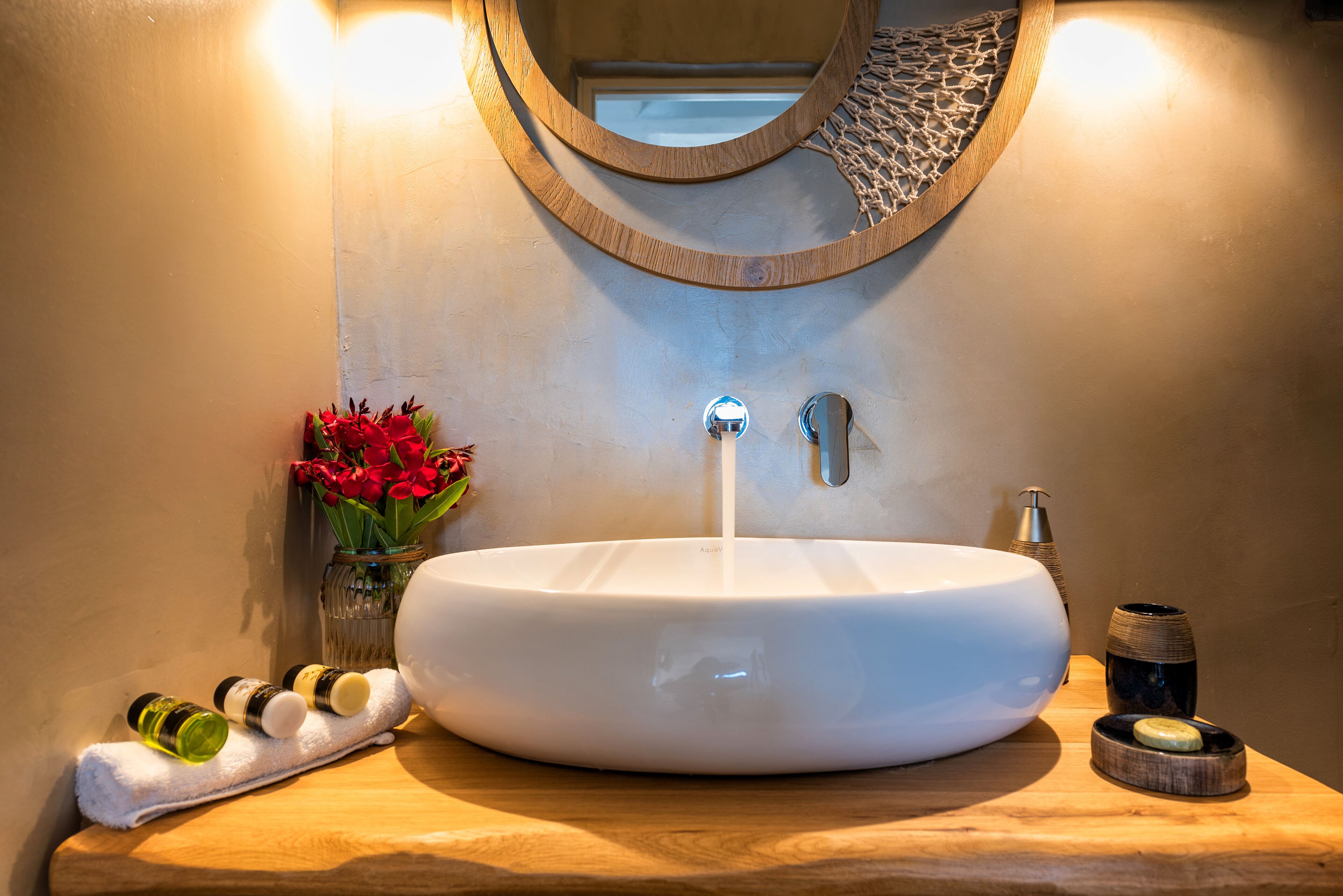 A bathroom with a large white sink, a mirror, and a wooden vanity.
