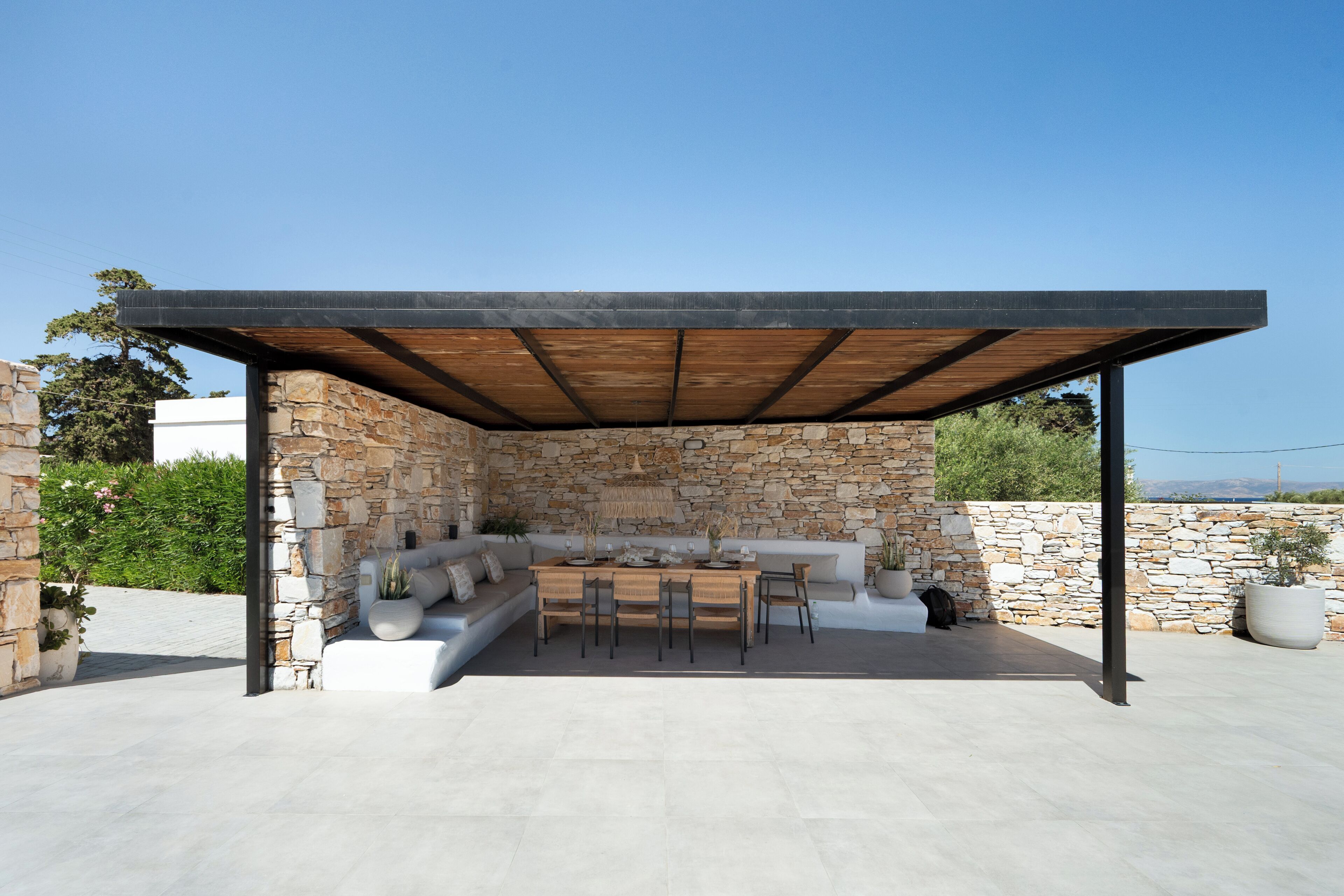An outdoor patio with a stone wall, a wooden table, and a seating area.