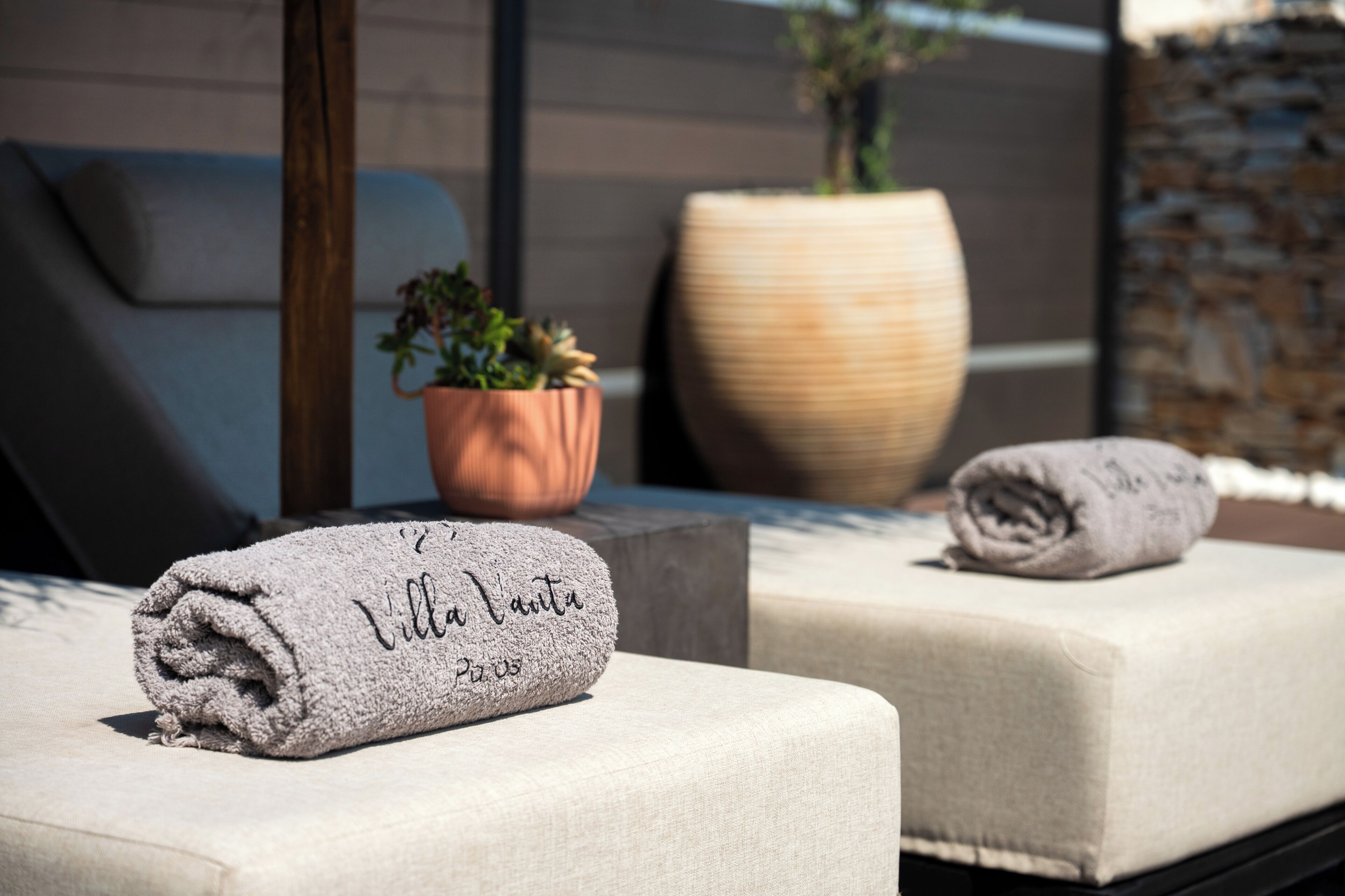 A spa area with two lounge chairs, a potted plant, and a large vase.