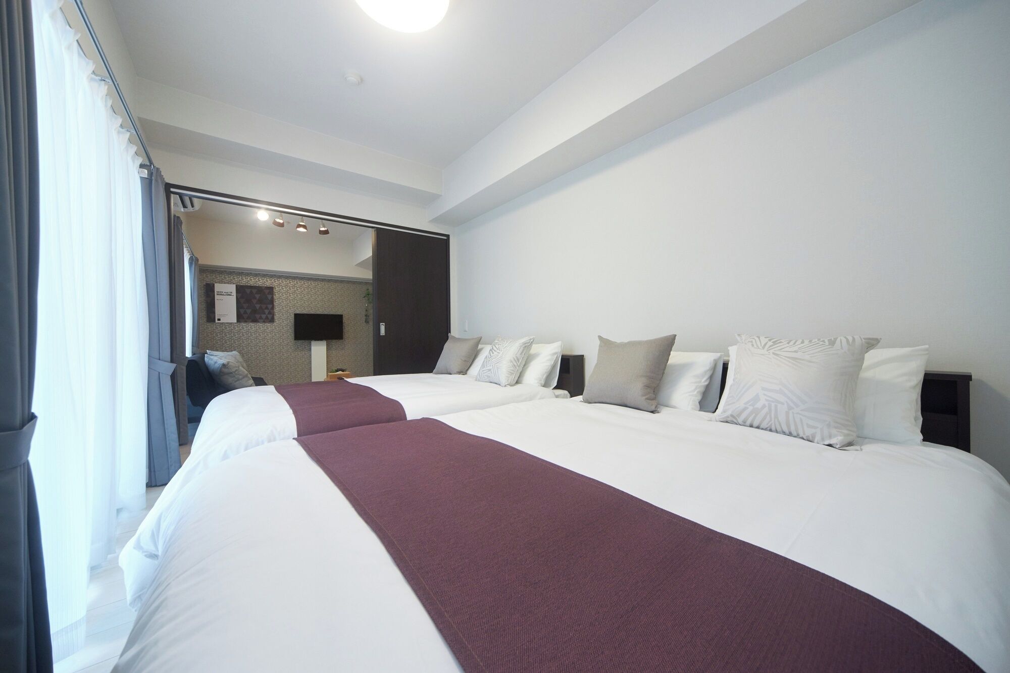 Une chambre d’hôtel avec deux grands lits, un téléviseur à écran plat et vue sur le couloir.