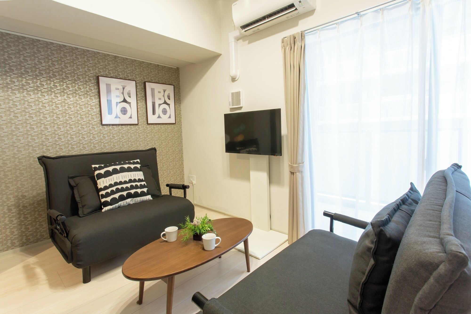 A modern living room with a sofa, a coffee table, a flat-screen TV, and a window with curtains.