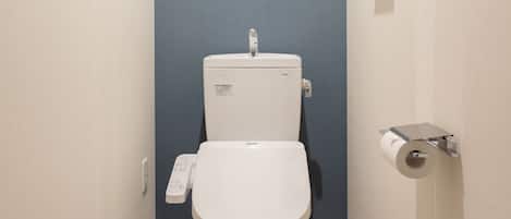 A modern toilet with a control panel, a toilet paper holder, and a blue wall.