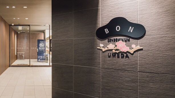 Une entrée moderne d’immeuble avec une enseigne indiquant « BON Condominium Umeda ».