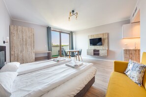 Une chambre d’hôtel avec un grand lit, un canapé, une télévision et un balcon équipé d’une table et de chaises.