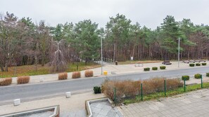 Un chemin pavé bordé de bancs, une route et une zone boisée.
