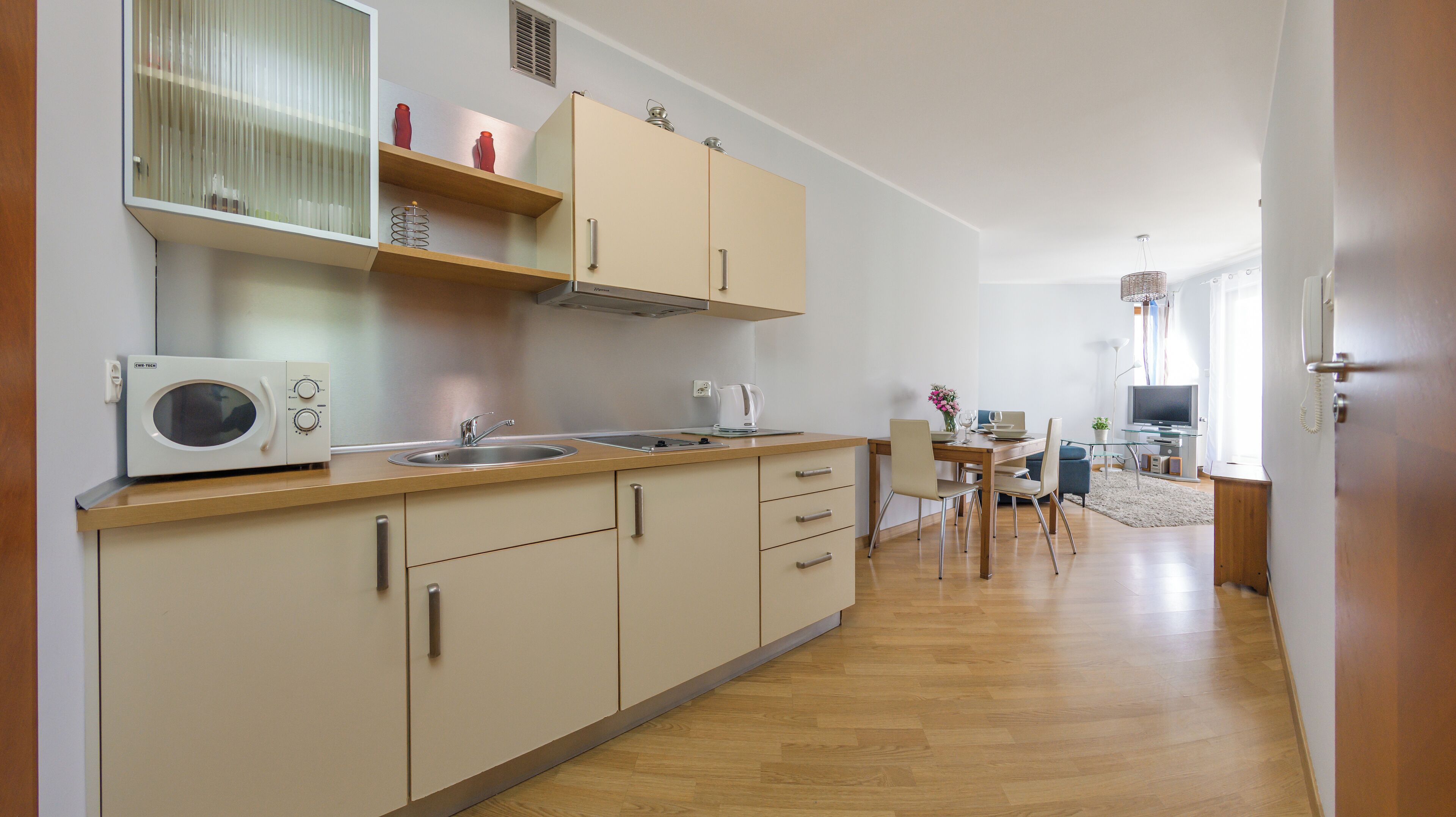 A modern kitchen with a microwave, sink, and wooden cabinets.