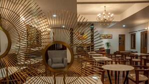 Un interior moderno con una zona de estar central, muebles de madera y una araña.