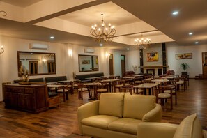 A spacious lobby with high ceilings, chandeliers, and a fireplace. There are multiple seating areas with tables and chairs. - Arotel SPA (Antsirabe)