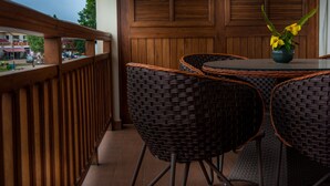 Un balcón con mobiliario de mimbre y una mesa con un jarrón de flores.