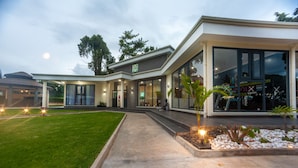 Una casa moderna de dos plantas con un porche cubierto, un césped cuidado y un gran ventanal que muestra texto relacionado con el ejercicio.