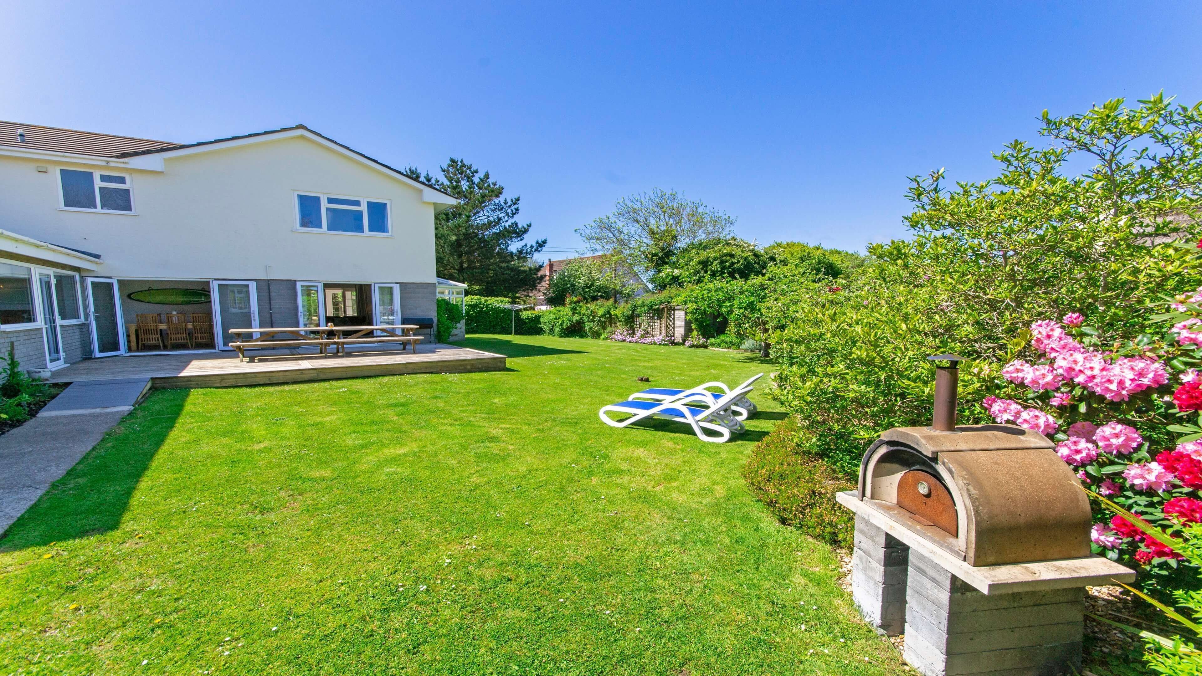 A house with a patio, a barbecue grill, and a lawn.